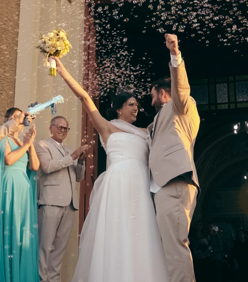 Casal celebrando com os braços erguidos e chuva de pétalas